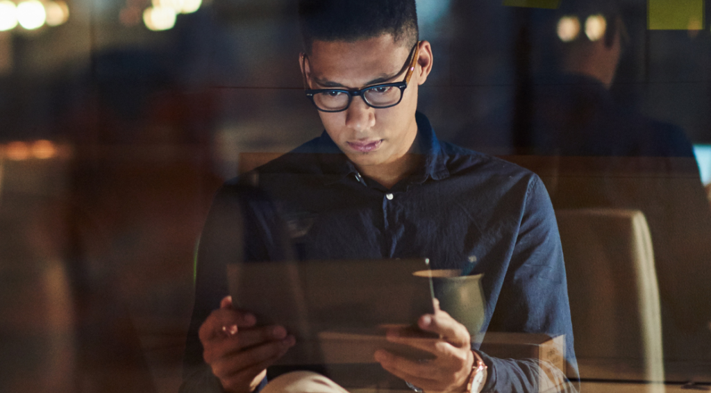 A man with glasses looking at his tablet device